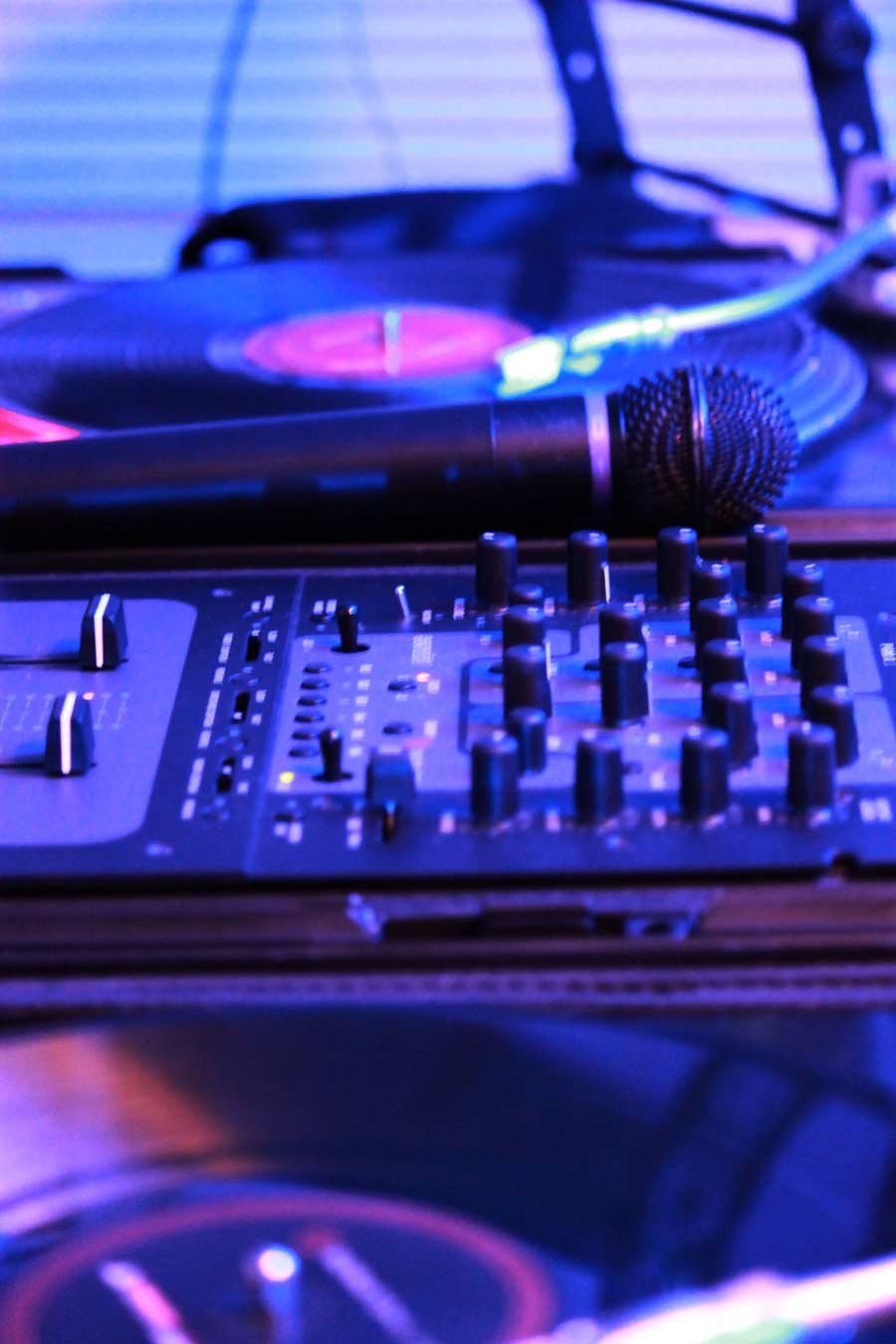 Close-up of turntables, mixer, and microphone mid-set